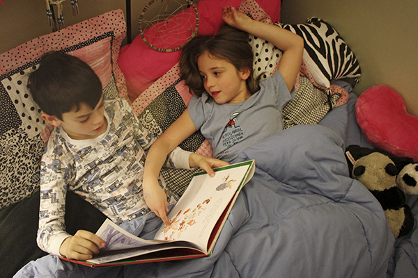 Two kids reading a book.