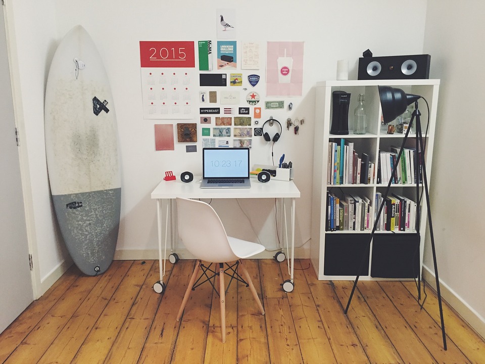 habitación con escritorio, librero, PC, lampara y tabla de surf